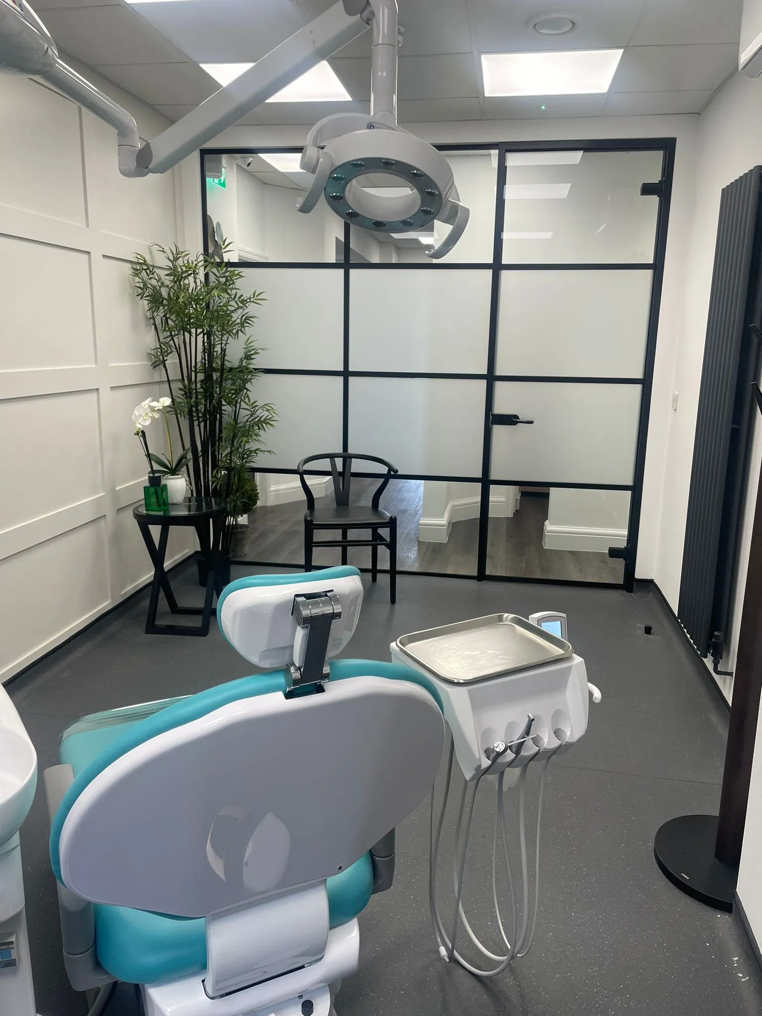 Teal dental chairs behind black-framed glazed screens at Infinity Dental Clinic, Leeds