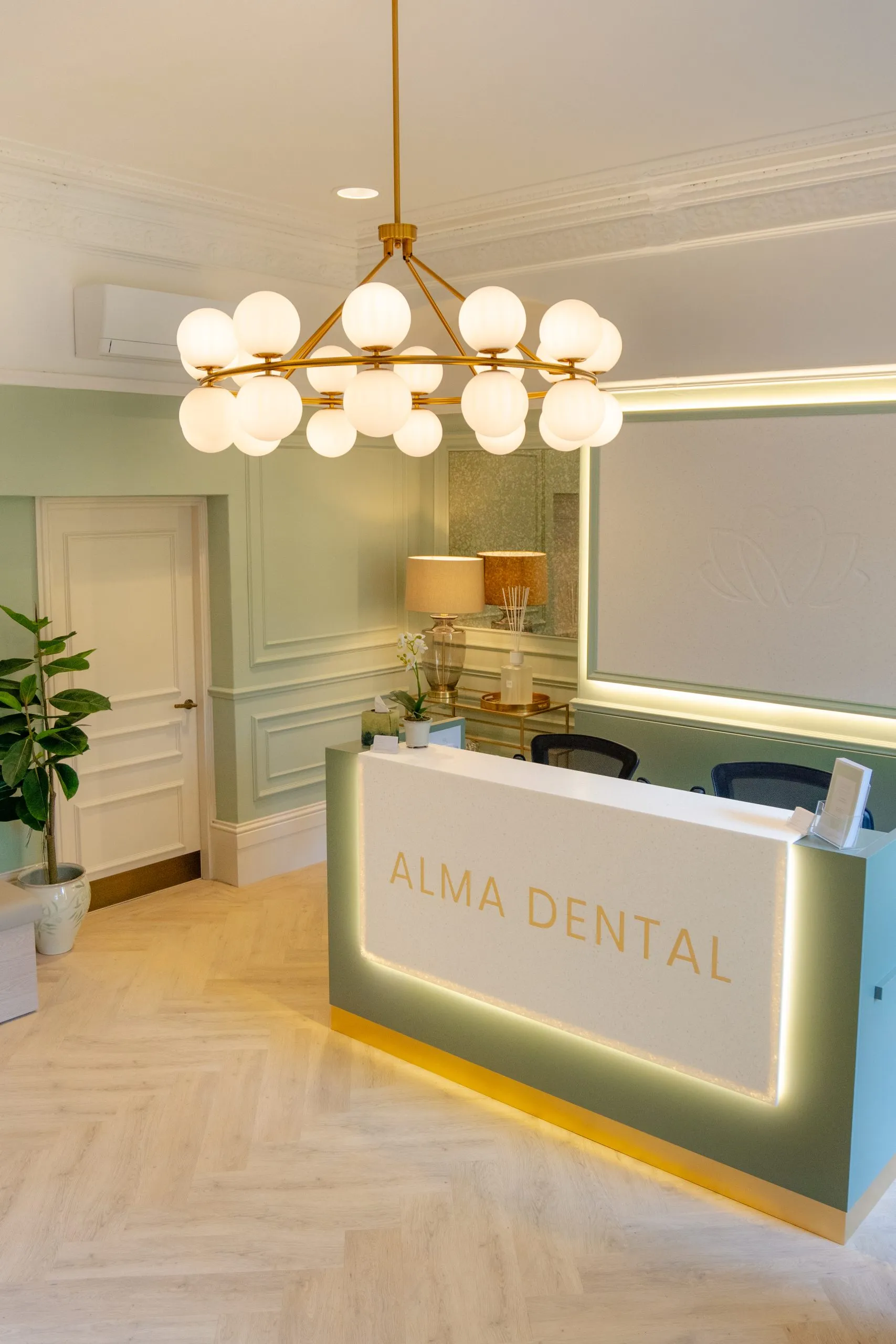 Backlit Alma Dental reception desk with sage panelling, North Shields