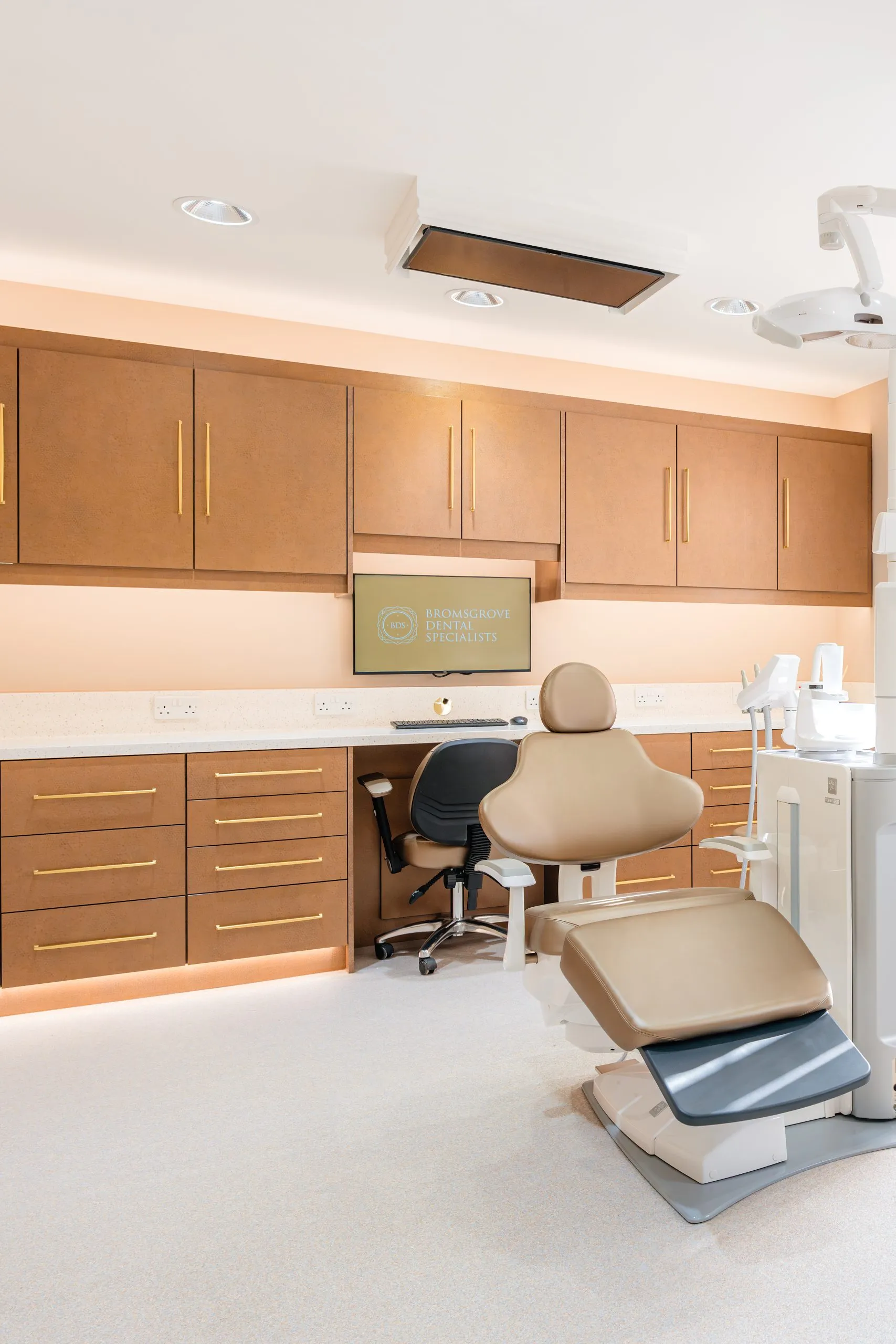 Dental surgery with bespoke tan cabinetry and integrated equipment at Bromsgrove Dental Specialists