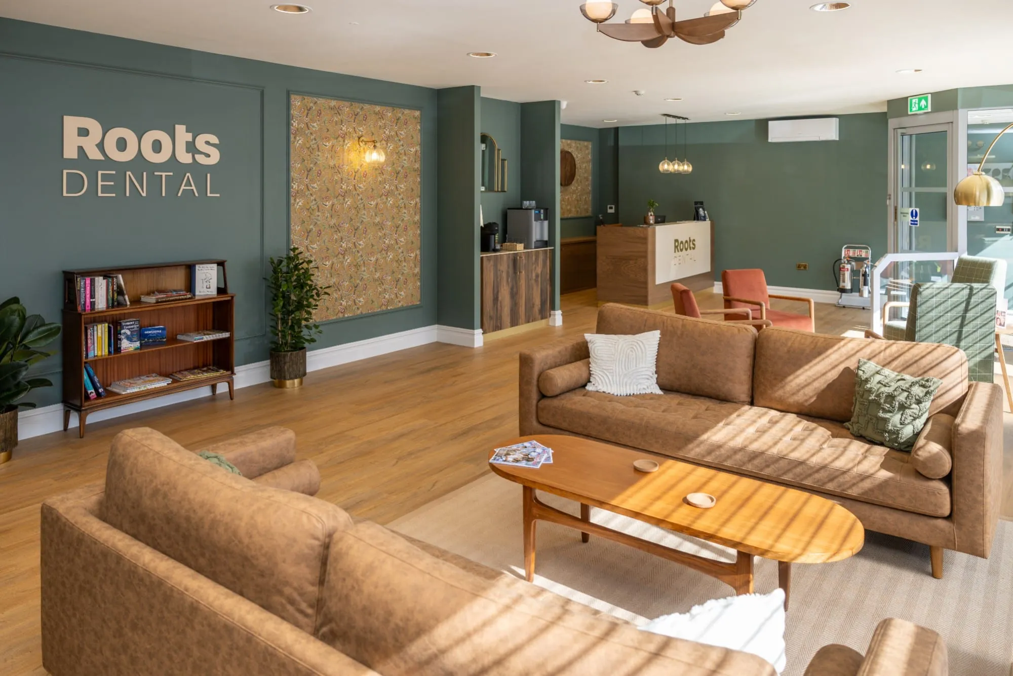 Waiting lounge with tan sofas, bookcase and green panelling at Roots Dental, Morpeth — the squat practice praised in this review